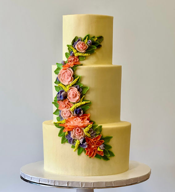 Three tier white cake with palette knife flower decoration up the front.