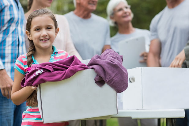 Young girl donating a box of clothes.