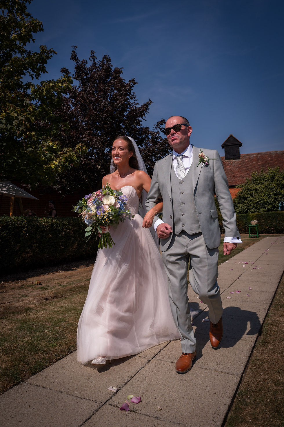 bride and father walking to ceremony at The Lawn, Rochford, with bouquet, confetti path