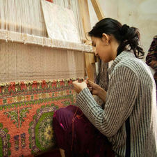Young artisan weaving a traditional carpet on a vertical loom in Tunisia.