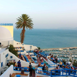 View of Sidi Bou Saïd overlooking the Mediterranean with people gathered along terraces and walkways