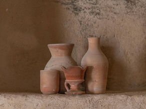 Handmade Tunisian clay vessels on a textured earthen surface, showing natural material tones and traditional ceramic forms