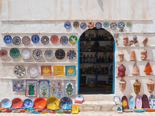 Devanture d’une boutique tunisienne avec objets artisanaux exposés : poteries, tapis, paniers et céramiques, photographiés sous lumière naturelle, dans leur environnement réel.