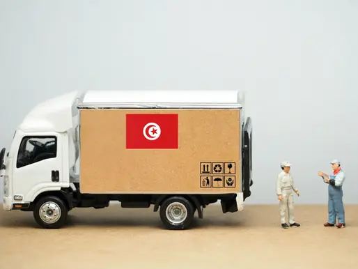 Miniature delivery truck with Tunisian flag and two figurines discussing logistics — symbolizing traceability and origin in artisan supply chain