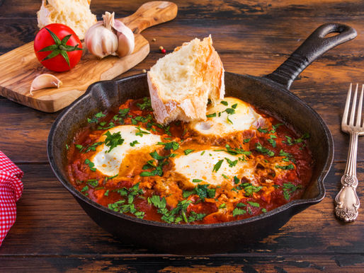 Poêle en fonte de chakchouka avec œufs, sauce tomate et persil, accompagnée de pain