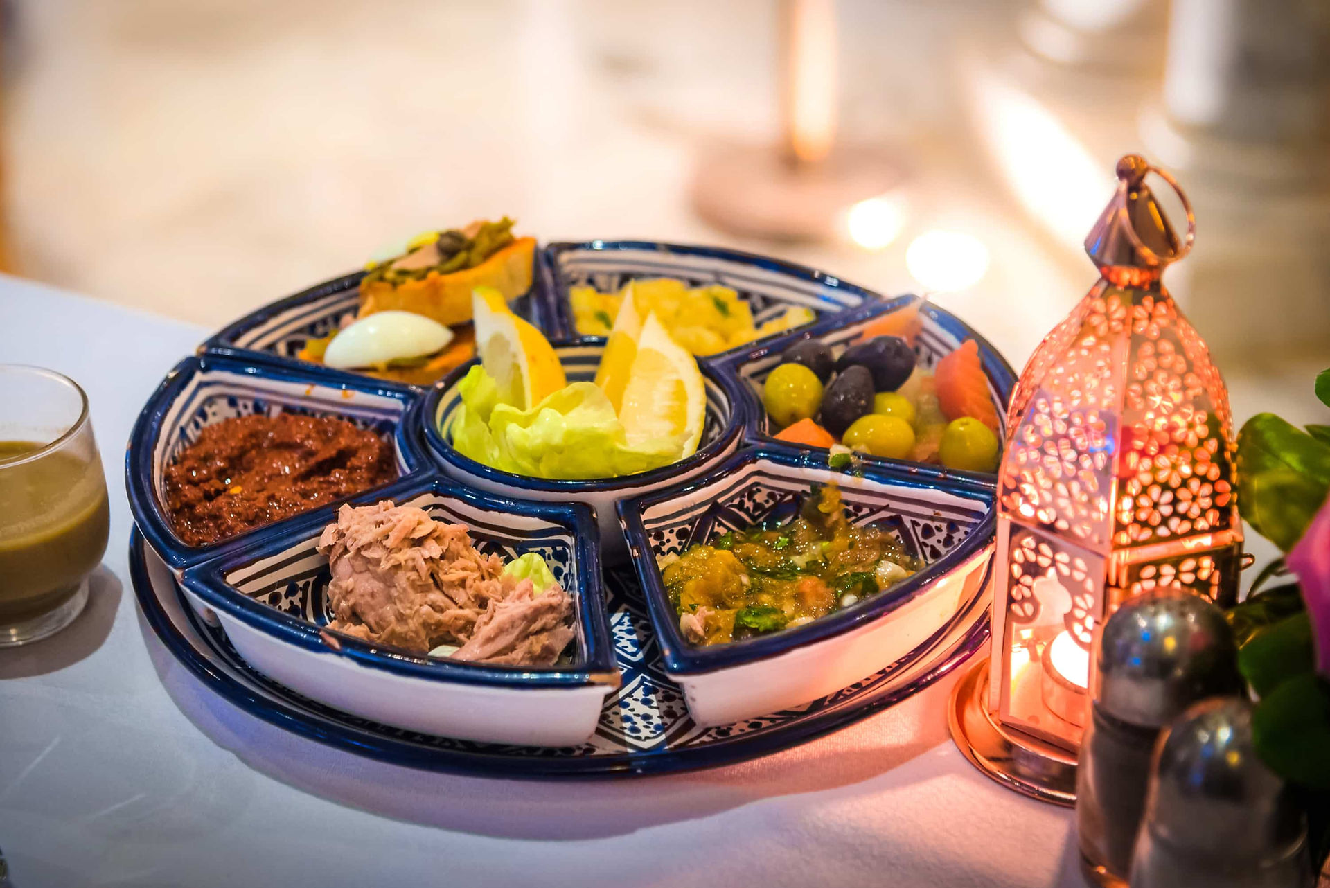 Tunisian ceramic serving dish filled with olives, lemon, and small foods on a dining table