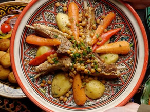 Tunisian ceramic serving platter with lamb, chickpeas, potatoes, and carrots on table