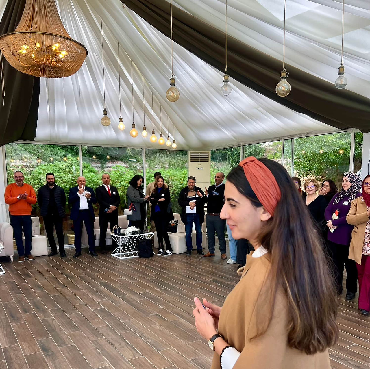 Woman speaking to a group of people gathered during a community and professional networking event.