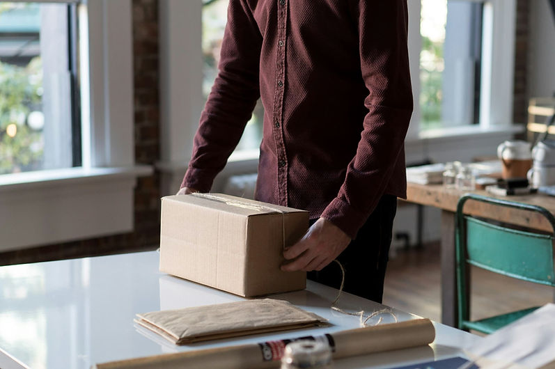 Person positioning a sealed cardboard parcel on a table during the order preparation process.