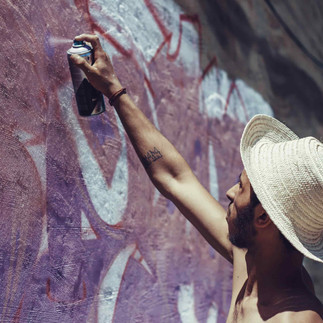 Young Tunisian artist painting graffiti on a wall in an urban neighborhood