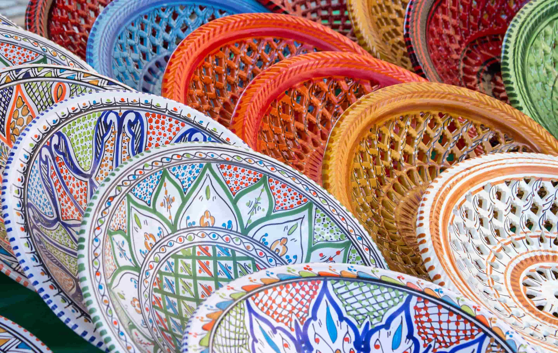 Hand-painted Tunisian ceramic plates with slight variations in pattern and surface, showing differences created during the making process.
