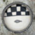Handmade Tunisian ceramic bowl with black-and-white geometric pattern on stone background.