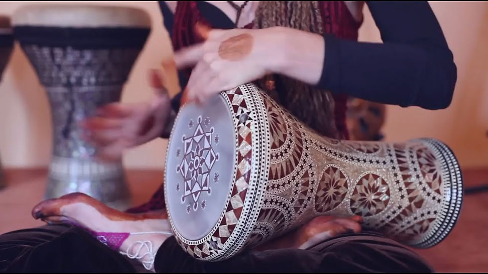 Person playing a decorated darbuka (goblet drum) with hands in motion, showing real use and rhythmic technique