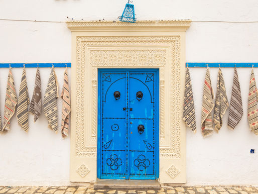 Traditional blue door in Tunisia with handmade textiles hanging on both sides