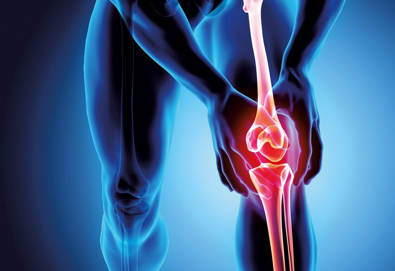 X-ray of a person holding a knee with red highlighted joint, indicating pain or injury. Blue tones dominate the background.