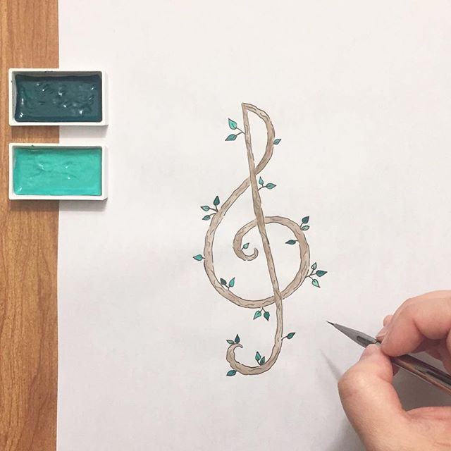 Kimberly's hand painting a wooden treble clef with leaves sprouting from it.