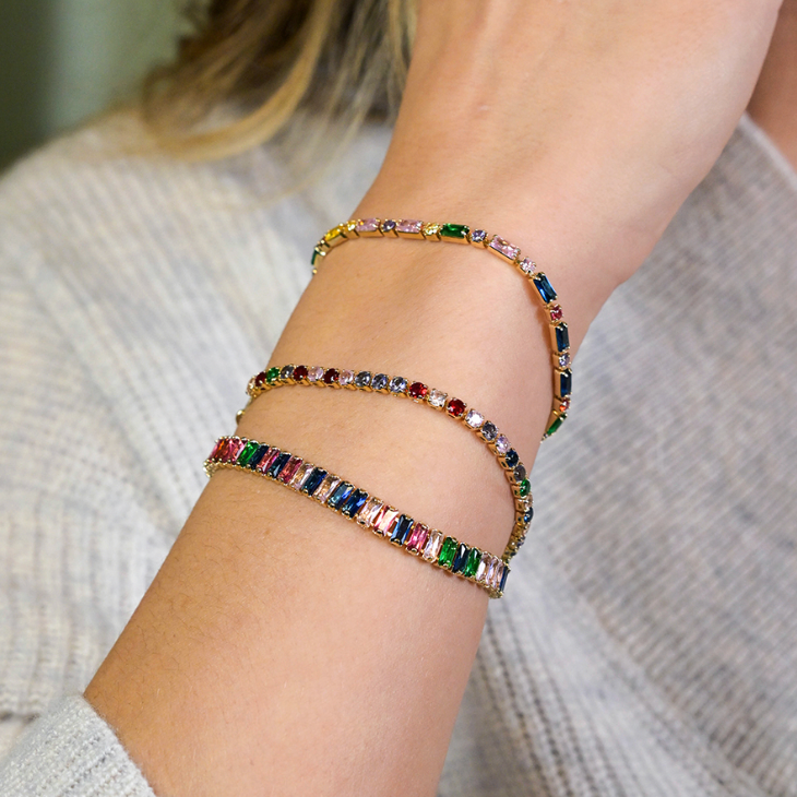Lady wearing Golden link chain bracelet with multicoloured crystals plus two other bracelets