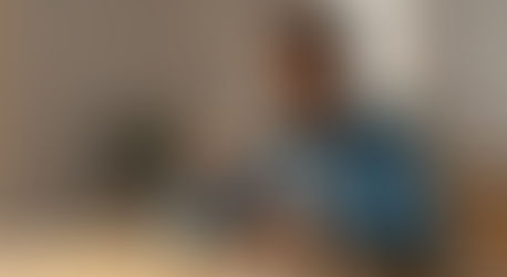 Persona latina observando un vaso de agua con limón en la mesa durante el desayuno, simbolizando la hidratación inteligente y la preparación para un día con energía.