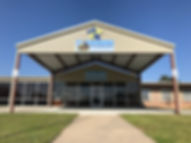 The front entrance of the building. A covered tan metal drive thru with the Making Abilities Count Logo