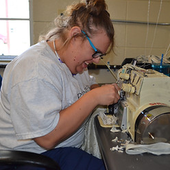 A happy student sewing for work.