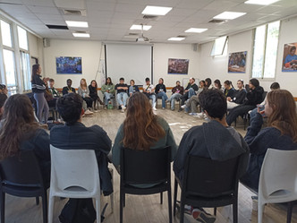 Trainees sit in a circle listening to a lecture