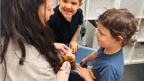 Two children looking at therapist while playing in sensory bin together