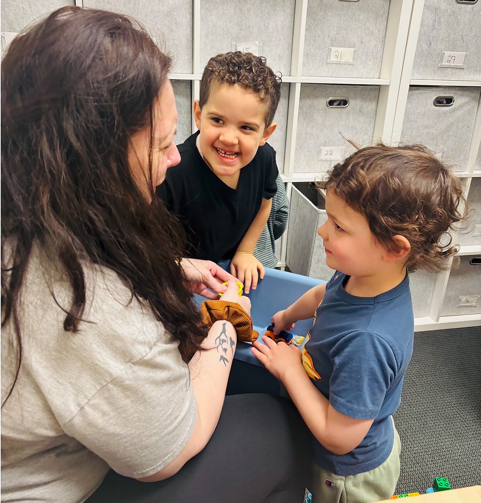 Two children looking at therapist while playing in sensory bin together