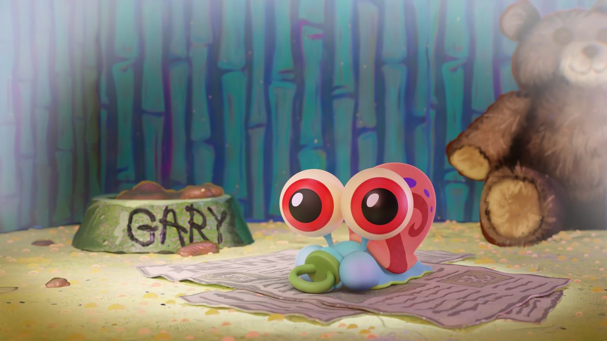 Baby Gary with huge eyes on a blanket next to his food bowl and a teddy bear