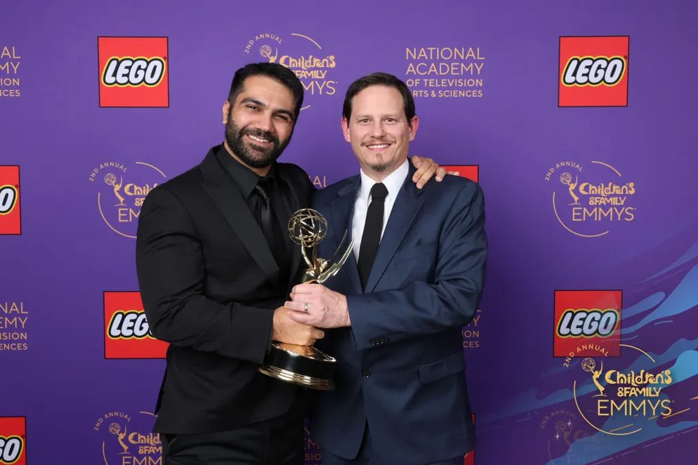 Adam holding an Emmy statuette beside Clay Morrow at a Children's and Family Emmys press wall