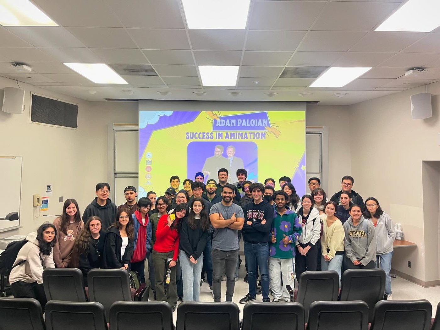 Adam, arms crossed, with a room full of UC Irvine students in front of the Success in Animation title slide