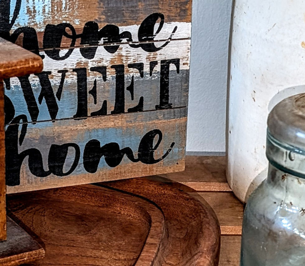 An estate sale display featuring an antique coffee grinder, 'Home Sweet Home' sign, and some vintage jars.