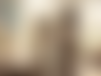 Person in beige clothing gazes into a mirror in a serene room with plants and a wall mural. An open notebook and pen sit on a wooden table.