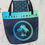 Thumbnail: Parri Jamaica beach bag on sand with palm logo design and matching pouch tucked inside top opening.