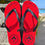 Thumbnail: Red Parri Jamaica flip flops with black straps and palm logo resting on a concrete block by the beach