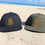 Thumbnail: Two Parri Jamaica snapback caps—one olive green, one black—with gold embroidered logos, resting on sandy beach with blurred o
