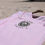 Thumbnail: Pink Parri Jamaica V-neck tee with black logo, place on the white sand.