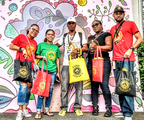 Group wearing Parri Jamaica shirts and holding branded tote bags, representing Jamaican culture, community, and local crafts