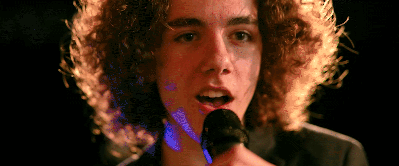 My Best Friend's Girl music video. A main singer at a micrphone as the camera pulls back to reveal two backup singers jump into frame.