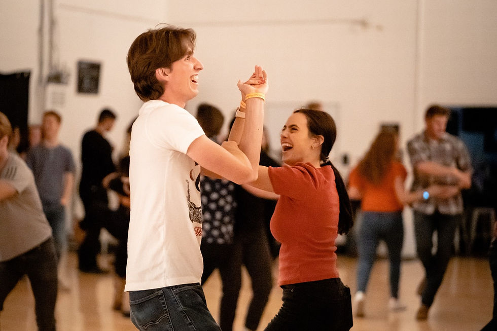 A couple faces each other while doing the window with their arms.