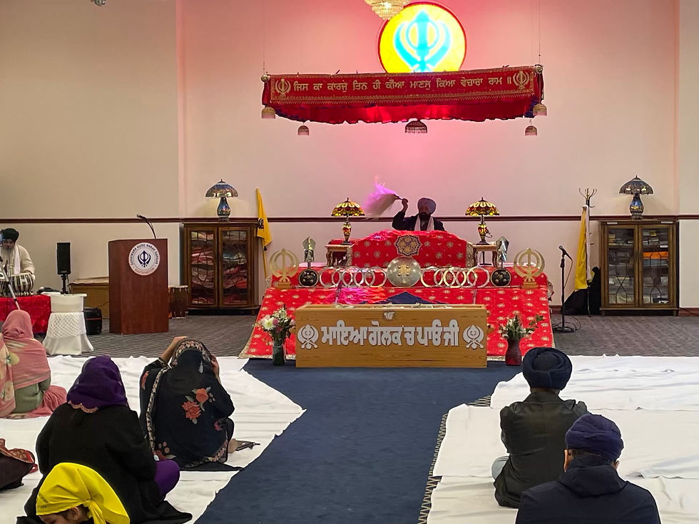 A view of the platform; the Guru Granth sits on a table between the two lamps.