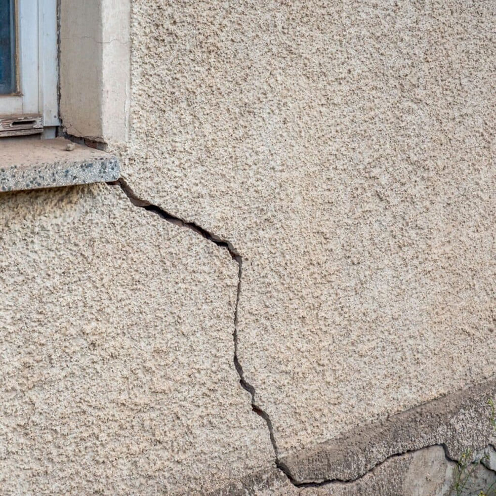Exterior wall with visible cracks near foundation