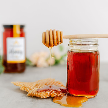 Lifestyle product photo of Appalachian Wax Works honey dripping from a honey dipper onto fresh honeycomb.