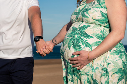 A close up of a pregnant woman holding hands with her partner on Seaton Sluice beach_maternity photography by Emma Solomon Photography