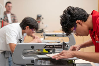 Young men learning woodworking under the guidance of a teacher.