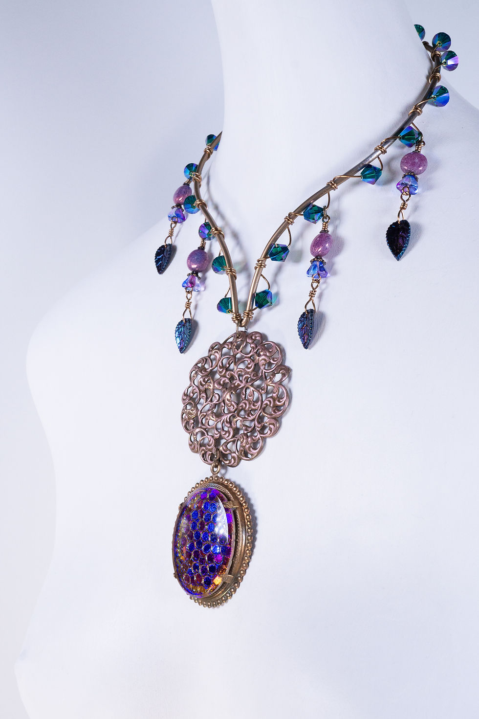 Thumbnail: Collar necklace, front right, crystals, drops, lg. brass filigree center, lg. vintage pattern glass focal, blue-purple-pink