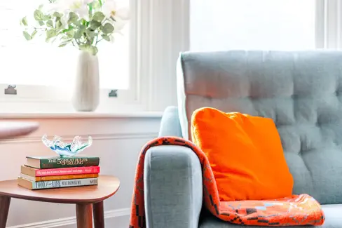 modern gray couch adorned with vibrant orange throw pillows, creating a striking contrast
