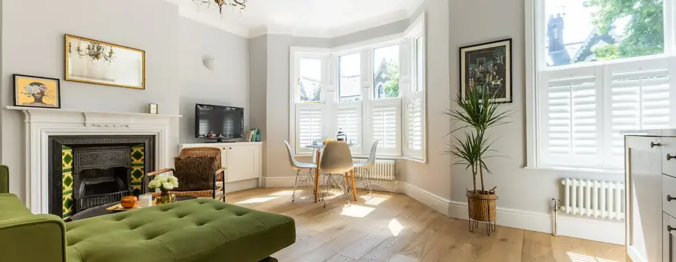 Cardiff property living space with a soft green plush couch, polished wood flooring, clean white walls, and a dining set including a table and chairs.