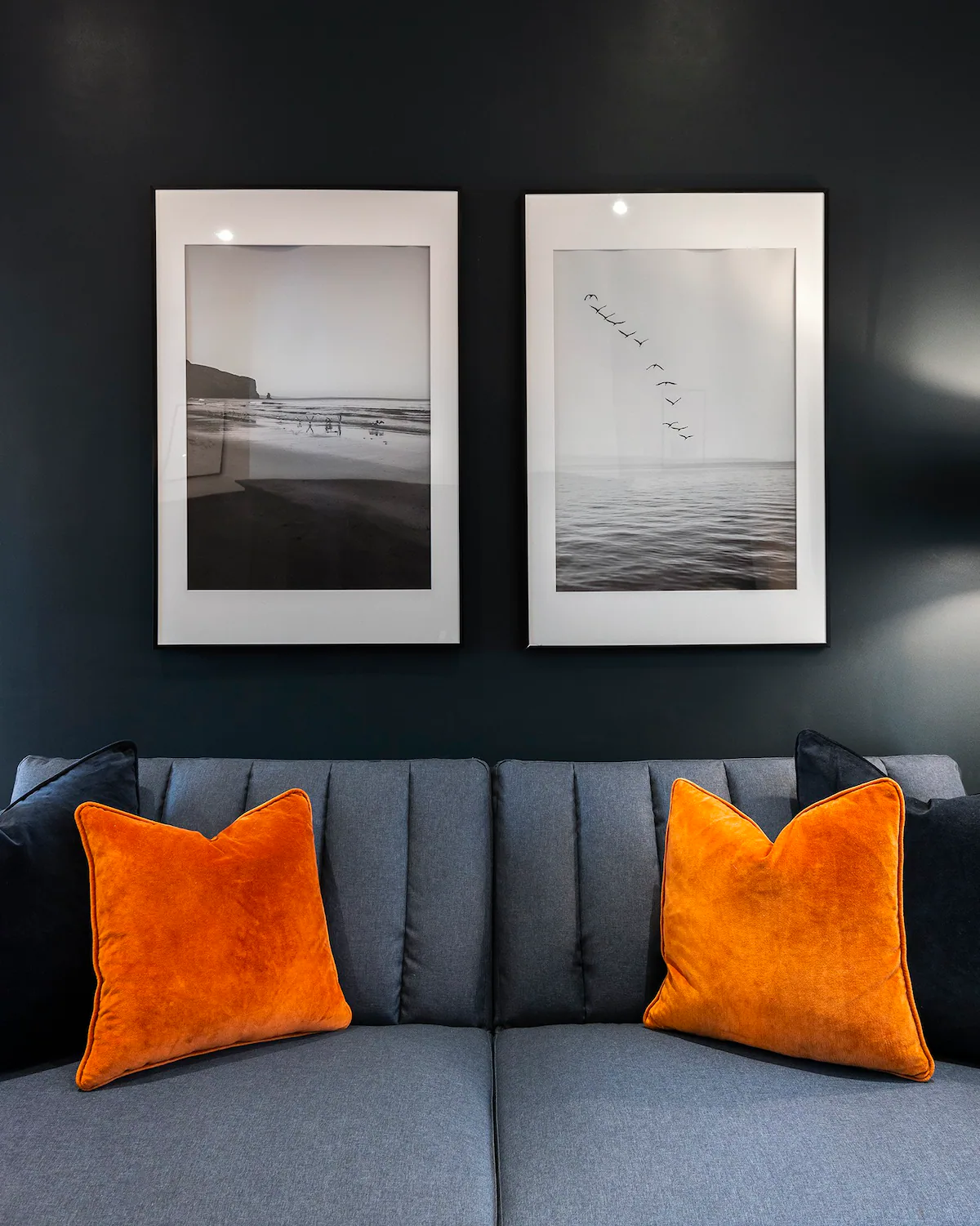 A dark blue couch with vibrant orange throw pillows, adding a pop of color and contrast to the room's decor