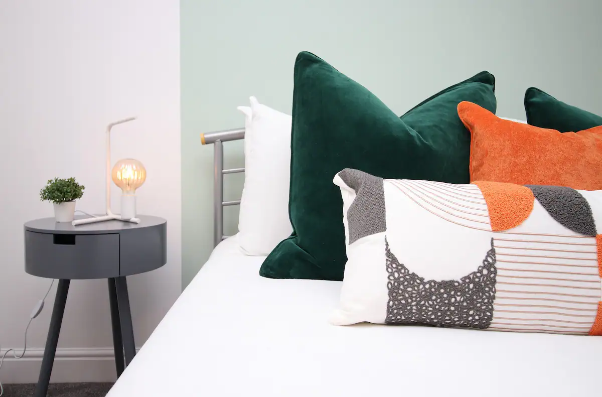 The comfortable bed at Dock House is adorned with colorful pillows, adding a vibrant touch to the cozy bedroom