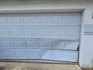 Dented and sagging panels on a white steel sectional double garage door in Orange County, CA.